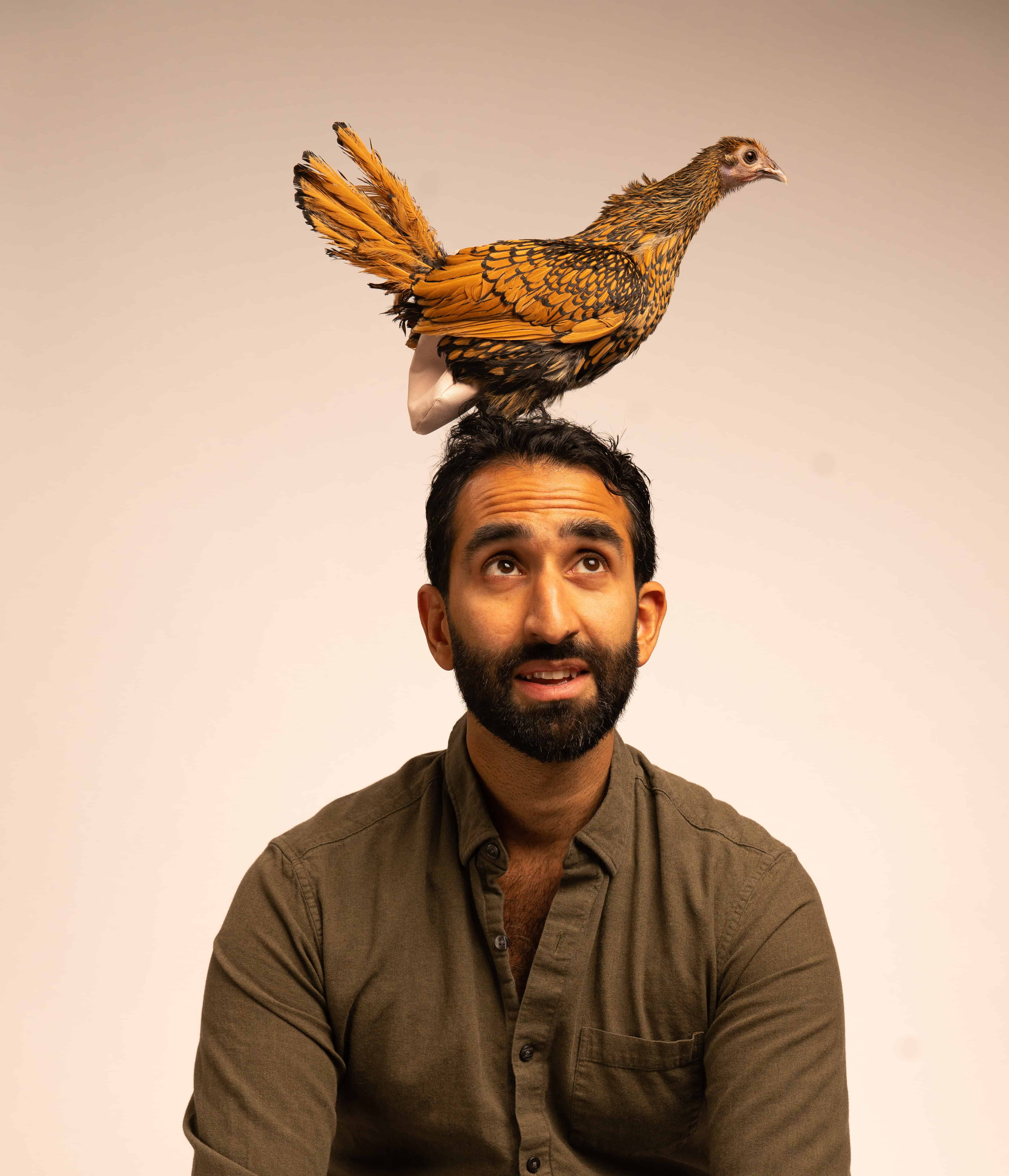 Manick Bhan balancing a chicken on his head for a photoshoot.