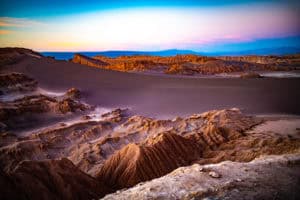 Breathtaking desert scene with rugged terrain and colorful sky at dusk.