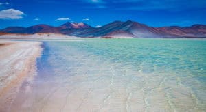 Beautiful salt lake reflecting vibrant blue sky and surrounding mountains.